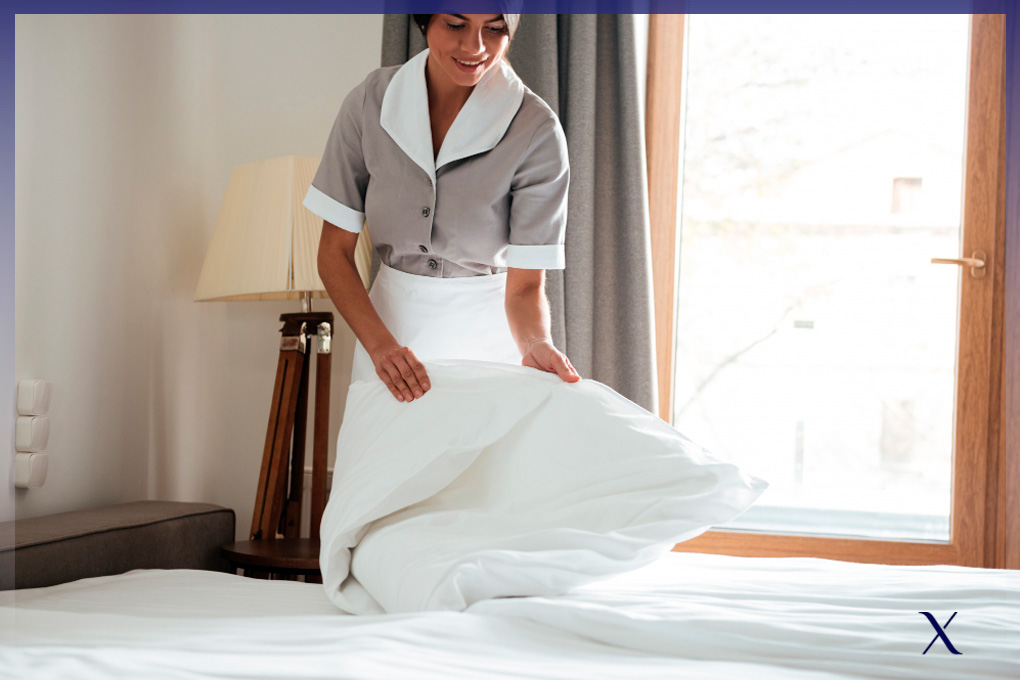camarera de pisos adecuando la lencería de una cama de hotel