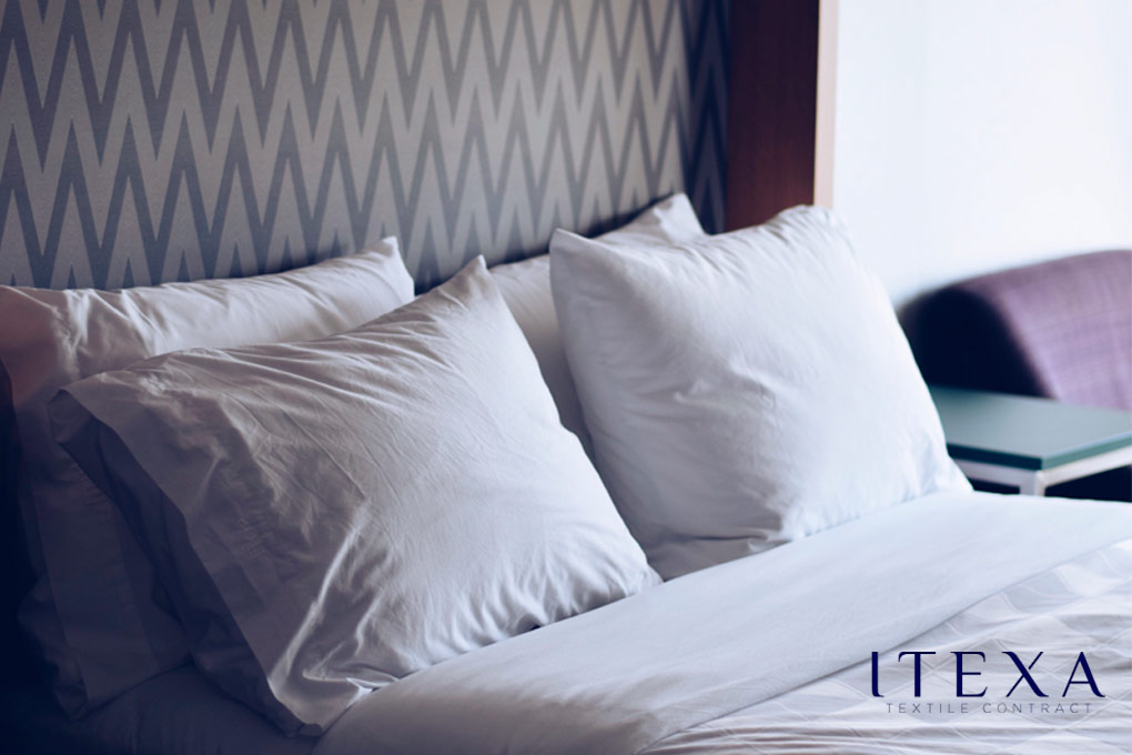 Mejores almohadas de hotel, cuatro, blancas e impolutas sobre la cama
