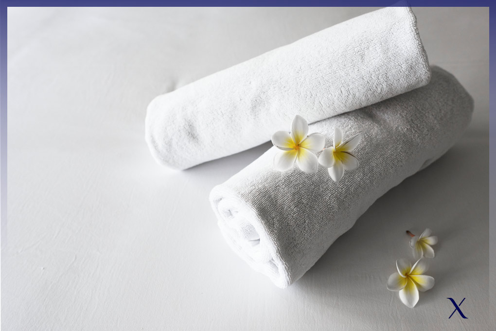 toallas blancas vistas desde arriba dobladas en forma de rollo con 3 pequeñas flores