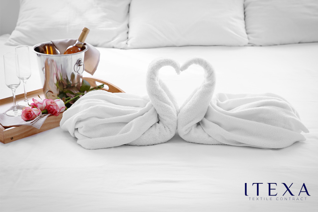 toallas blancas en forma de cisne sobre una cama de hotel